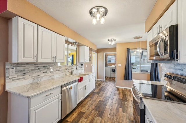 1021 Augusta Dr, Sun City Center, FL 33573 - kitchen with white cabinetry, washing machine and clothes dryer, an inviting chandelier, and stainless steel appliances