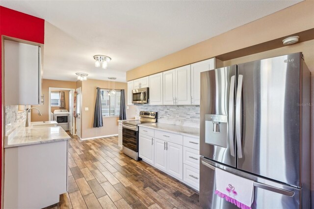 1021 Augusta Dr, Sun City Center, FL 33573 - kitchen with a sink, washer / dryer, white cabinetry, and stainless steel appliances