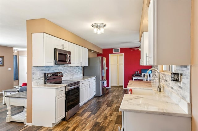 1021 Augusta Dr, Sun City Center, FL 33573 - kitchen with dark wood-style floors, visible vents, a sink, white cabinets, and appliances with stainless steel finishes