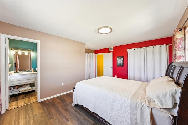 1021 Augusta Dr, Sun City Center, FL 33573 - bedroom featuring wood finished floors, visible vents, baseboards, a sink, and ensuite bathroom