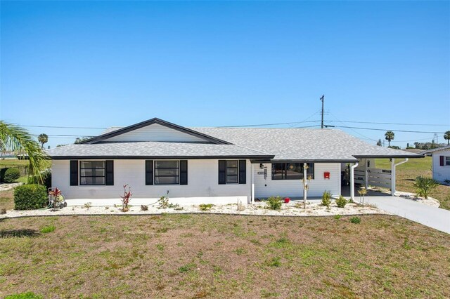 1021 Augusta Dr, Sun City Center, FL 33573 - ranch-style house featuring a carport, driveway, a shingled roof, and a front lawn