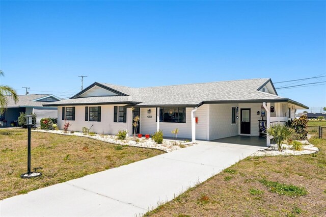 1021 Augusta Dr, Sun City Center, FL 33573 - ranch-style house featuring an attached carport, roof with shingles, concrete driveway, and a front lawn