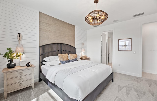 bedroom featuring visible vents, light colored carpet, an accent wall, and baseboards