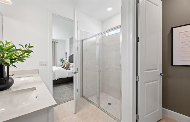 ensuite bathroom featuring ensuite bathroom, a sink, a shower stall, double vanity, and baseboards