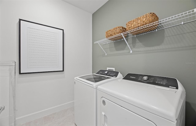 washroom with light tile patterned floors, baseboards, washing machine and dryer, and laundry area