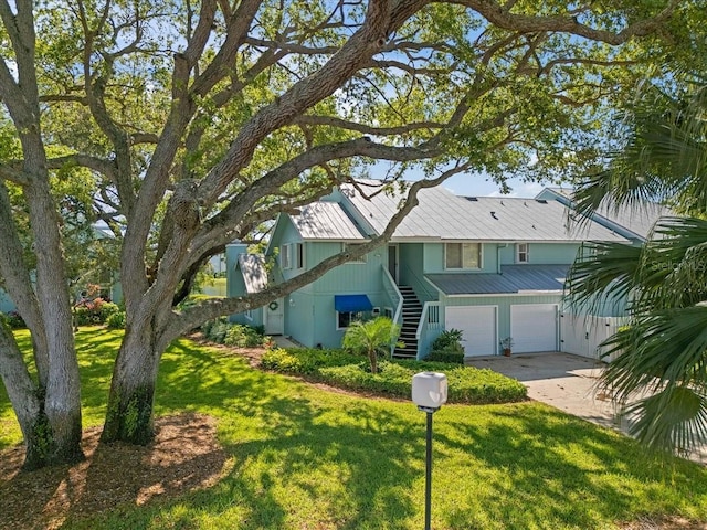 view of front facade with stairway, concrete driveway, a garage, and a front yard