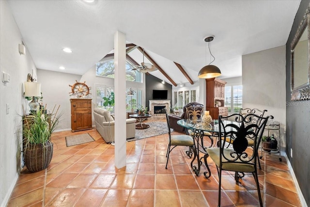 dining area with a fireplace with raised hearth, baseboards, vaulted ceiling, light tile patterned floors, and a ceiling fan