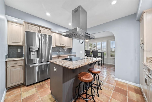 kitchen with a kitchen island, island exhaust hood, stainless steel fridge with ice dispenser, arched walkways, and black electric cooktop