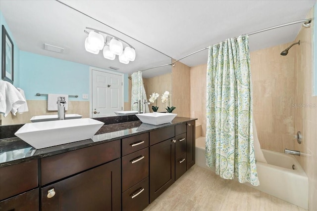 bathroom featuring a sink, shower / bath combo with shower curtain, and double vanity