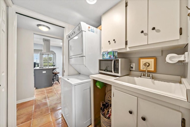 laundry room featuring a sink, light tile patterned floors, and stacked washing maching and dryer