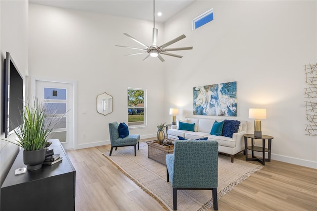 living room featuring a high ceiling, light wood-style floors, and ceiling fan