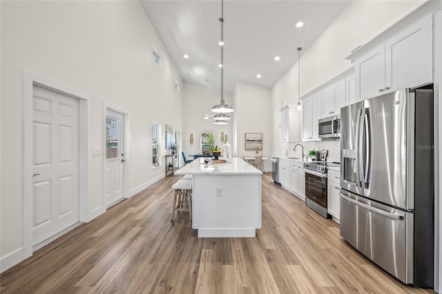 kitchen featuring appliances with stainless steel finishes, a breakfast bar, light wood-type flooring, and a sink