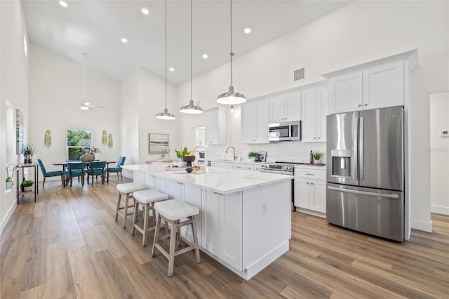 kitchen with visible vents, a breakfast bar, a sink, white cabinetry, and stainless steel appliances