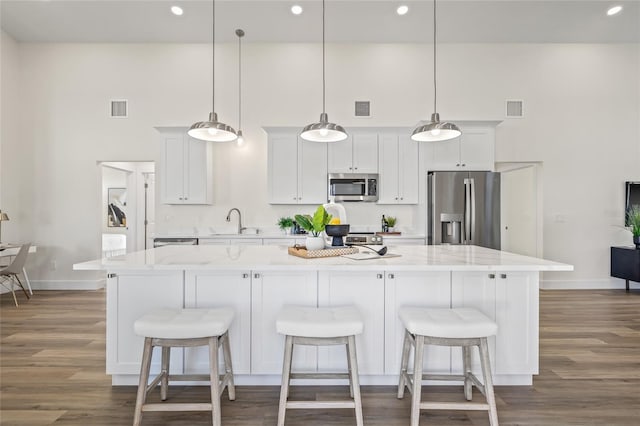 kitchen with visible vents, a kitchen island, appliances with stainless steel finishes, and dark wood-style floors