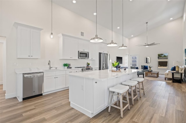 kitchen with a sink, open floor plan, white cabinetry, stainless steel appliances, and ceiling fan