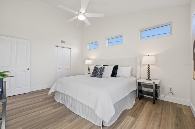 bedroom with a closet, visible vents, baseboards, and wood finished floors