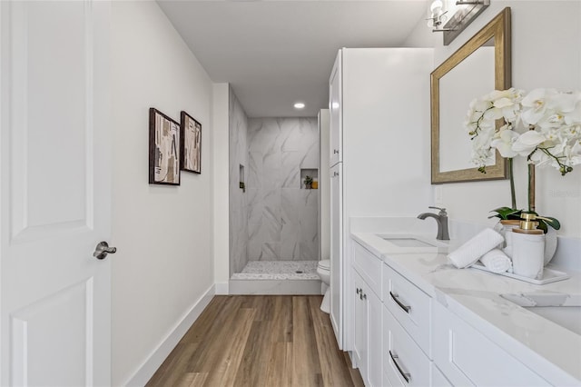 full bath with vanity, wood finished floors, baseboards, a marble finish shower, and toilet