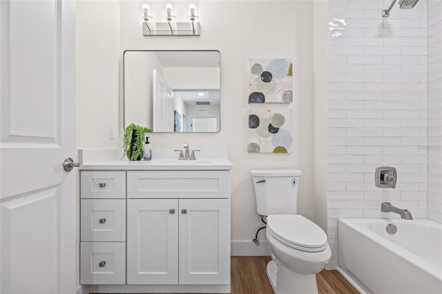 full bath featuring vanity, washtub / shower combination, wood finished floors, baseboards, and toilet