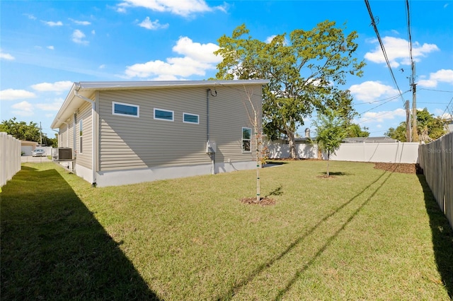 back of property with a lawn, central AC, and a fenced backyard