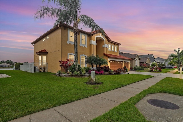 mediterranean / spanish home featuring fence, concrete driveway, a tile roof, a front yard, and stucco siding