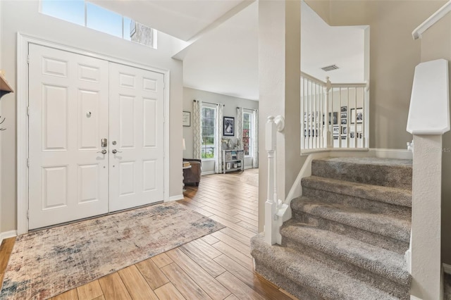 entryway featuring stairway, wood finished floors, visible vents, and baseboards