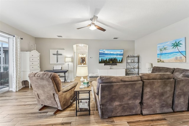 living room featuring wood finished floors, a ceiling fan, arched walkways, and visible vents