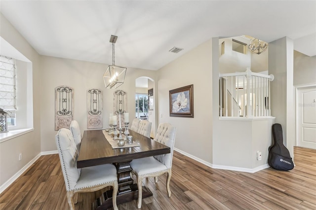 dining room with wood finished floors, visible vents, baseboards, arched walkways, and a chandelier