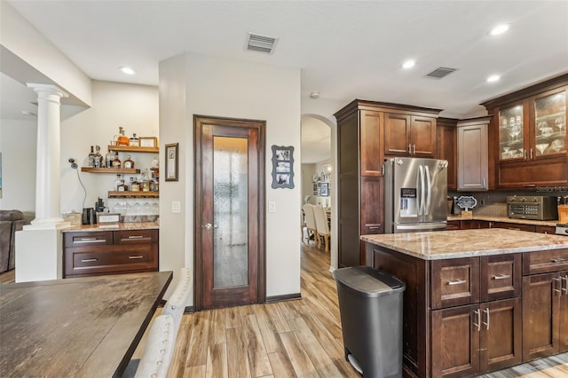 kitchen featuring visible vents, light wood-style flooring, stainless steel refrigerator with ice dispenser, and light stone countertops