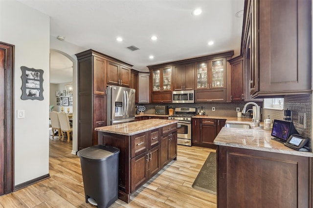 kitchen featuring arched walkways, stainless steel appliances, tasteful backsplash, and a sink