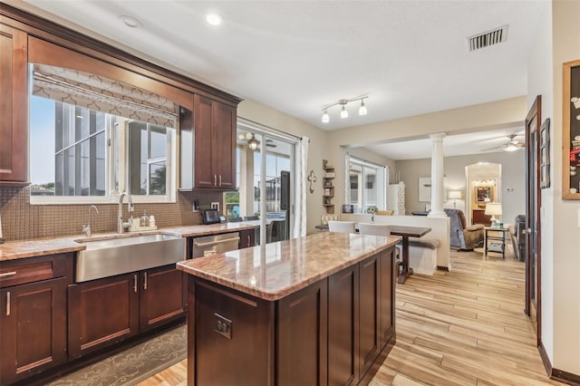 kitchen featuring light stone countertops, visible vents, decorative columns, a sink, and tasteful backsplash