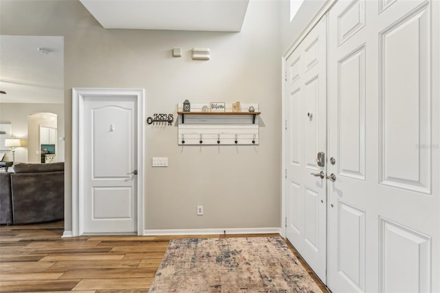 interior space featuring arched walkways, light wood-type flooring, and baseboards