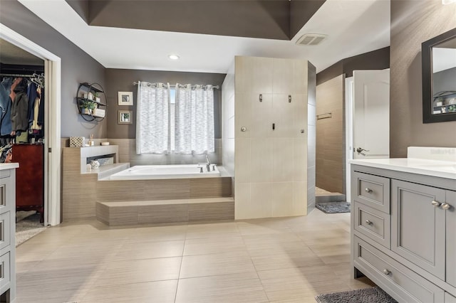 bathroom with a garden tub, vanity, tile patterned flooring, walk in shower, and a spacious closet