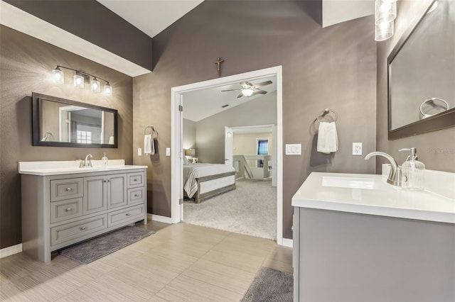 bathroom featuring vanity, lofted ceiling, a ceiling fan, and baseboards