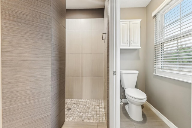 bathroom featuring baseboards, toilet, and a stall shower