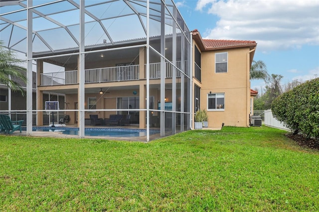 back of house with stucco siding, a lawn, a tile roof, a balcony, and central AC unit