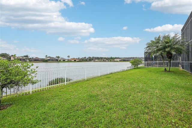 view of yard with glass enclosure, a fenced backyard, and a water view