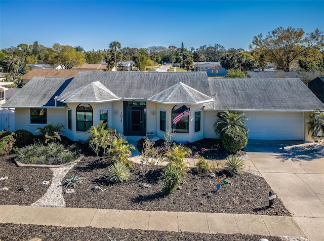 ranch-style home featuring an attached garage, driveway, and stucco siding