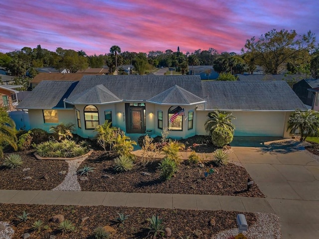 ranch-style home featuring stucco siding, a garage, and driveway