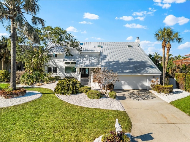 517 Belle Isle Ave, Belleair Beach, FL 33786 - view of front of home featuring driveway, a front yard, a standing seam roof, a chimney, and metal roof