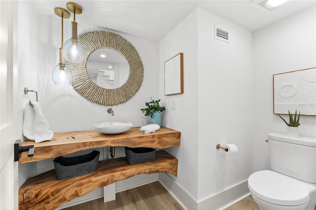 517 Belle Isle Ave, Belleair Beach, FL 33786 - bathroom with toilet, baseboards, a sink, visible vents, and wood finished floors