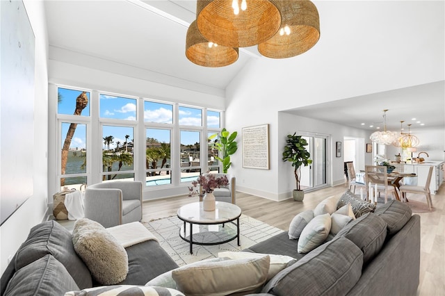 517 Belle Isle Ave, Belleair Beach, FL 33786 - living room with light wood-style flooring, high vaulted ceiling, baseboards, and a chandelier