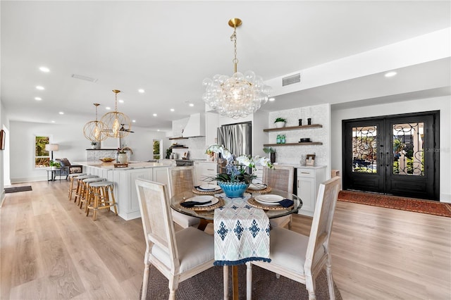 517 Belle Isle Ave, Belleair Beach, FL 33786 - dining space with light wood-type flooring, visible vents, and a notable chandelier