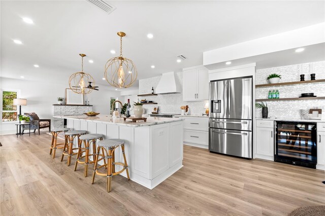 517 Belle Isle Ave, Belleair Beach, FL 33786 - kitchen with white cabinets, stainless steel fridge, premium range hood, open shelves, and beverage cooler