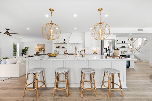 517 Belle Isle Ave, Belleair Beach, FL 33786 - kitchen featuring stainless steel refrigerator with ice dispenser, open shelves, custom range hood, a sink, and visible vents