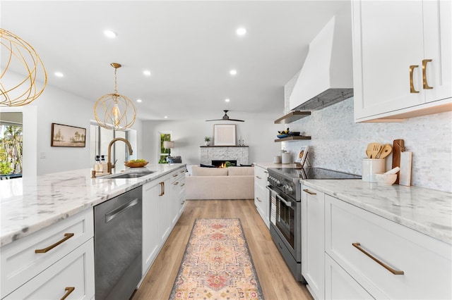 517 Belle Isle Ave, Belleair Beach, FL 33786 - kitchen featuring white cabinetry, stainless steel appliances, a sink, a stone fireplace, and custom exhaust hood