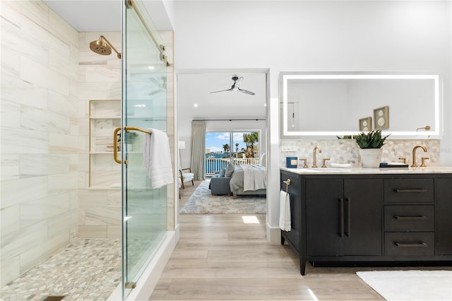 517 Belle Isle Ave, Belleair Beach, FL 33786 - ensuite bathroom featuring connected bathroom, backsplash, a shower stall, wood finished floors, and double vanity