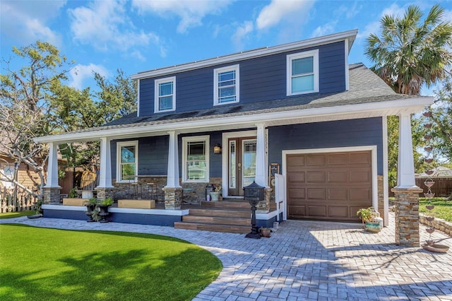 view of front facade featuring decorative driveway, a porch, a front lawn, and a shingled roof