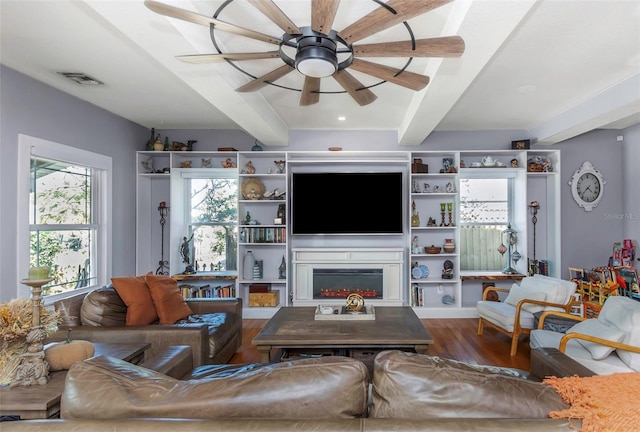 living room featuring beamed ceiling, a ceiling fan, visible vents, and wood finished floors