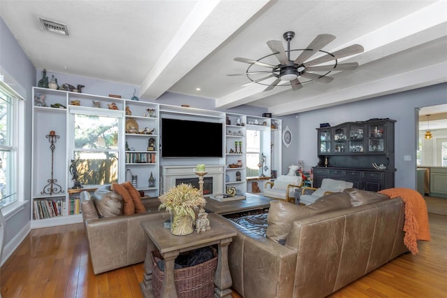 living room featuring visible vents, beamed ceiling, hardwood / wood-style flooring, a healthy amount of sunlight, and ceiling fan