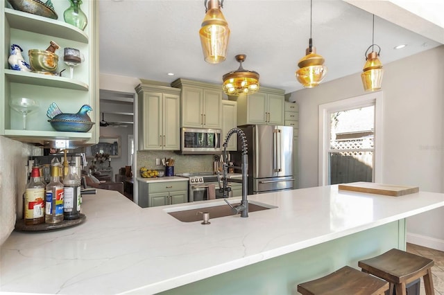 kitchen with light stone countertops, a sink, stainless steel appliances, a kitchen bar, and tasteful backsplash